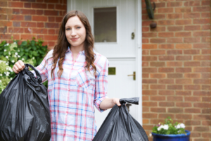 a woman in a plaid shirt is holding two black garbage bags
