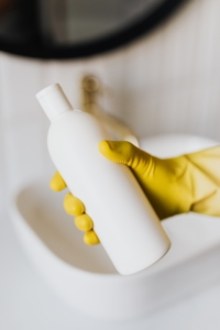 Gloved hand holding a white shampoo bottle