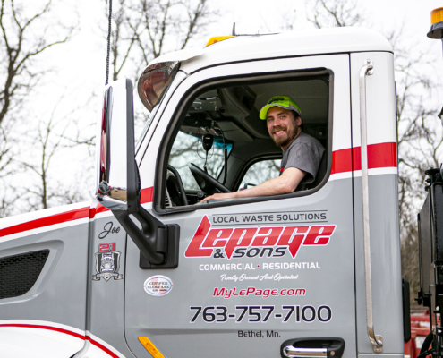 Man smiling in the driver's seat of a garbage truck